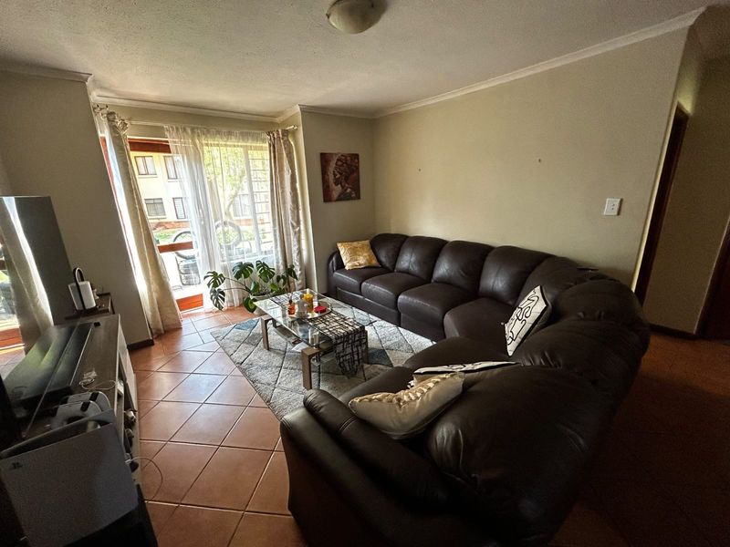 A comfortable living room featuring tiled flooring, coved ceilings, and a sliding glass door providing access to the exterior.