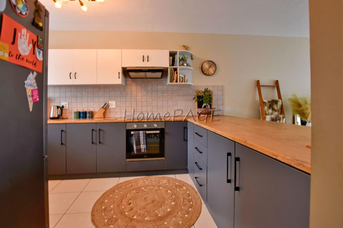 Modern kitchen featuring two-tone cabinetry, wooden countertops, tiled backsplash, built-in oven, and extractor fan.