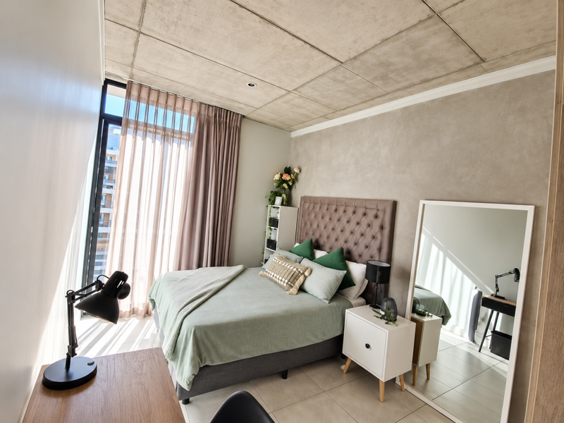 Modern bedroom featuring an exposed concrete ceiling, large floor-to-ceiling window with curtains, and neutral tiled flooring in a contemporary apartment setting.