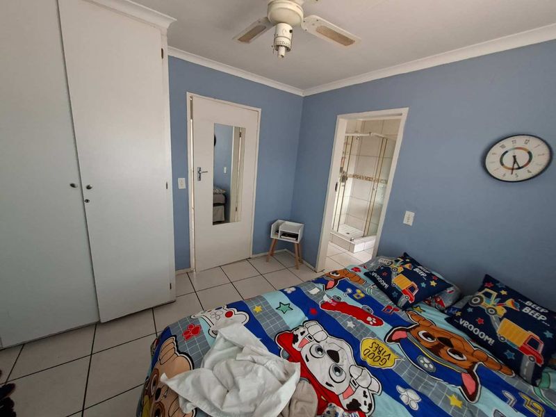A bedroom featuring tiled flooring, a built-in wardrobe, a ceiling fan, and direct access to an en-suite bathroom.