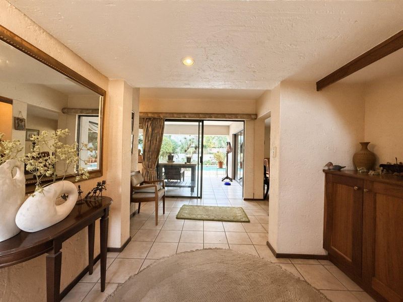 Welcoming entrance hall featuring tiled flooring, recessed lighting, and sliding glass doors providing a clear view through to the outdoor patio and pool area.
