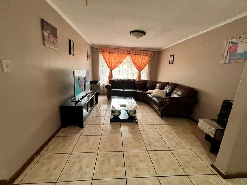 A living room featuring ceramic floor tiles, coved cornicing, and a central flush mount light fixture.