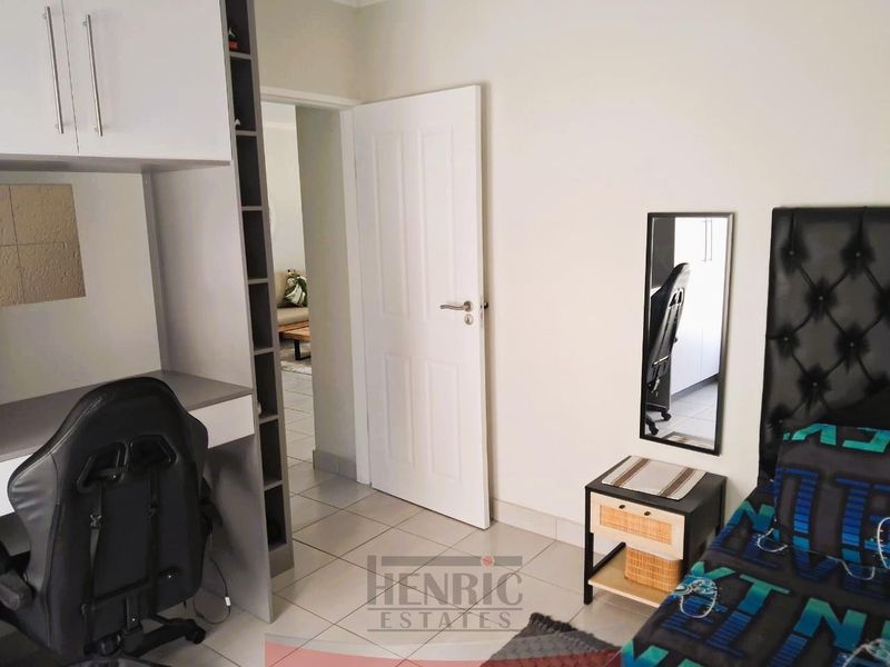 A bedroom featuring tiled flooring, a built-in desk with integrated shelving, and a neutral interior finish.