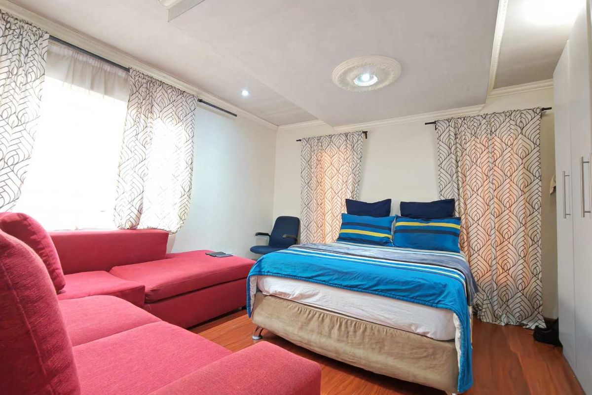 A spacious bedroom featuring laminate flooring, a built-in wardrobe, and decorative ceiling detailing, offering a comfortable and functional living space.