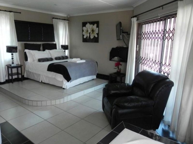 Spacious bedroom featuring a raised sleeping platform, tiled flooring, and direct access to the outdoors through a sliding door with security gate.