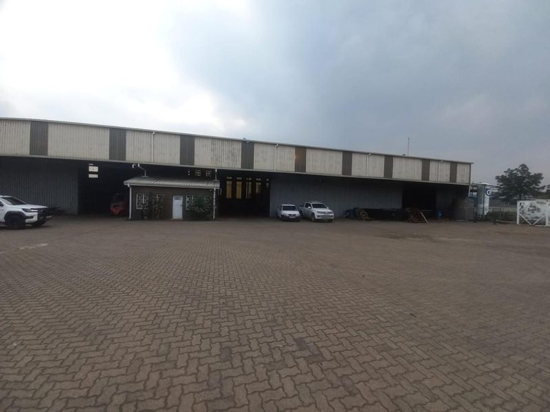 Industrial warehouse facility featuring a large paved yard area and corrugated metal exterior cladding with an integrated office section.