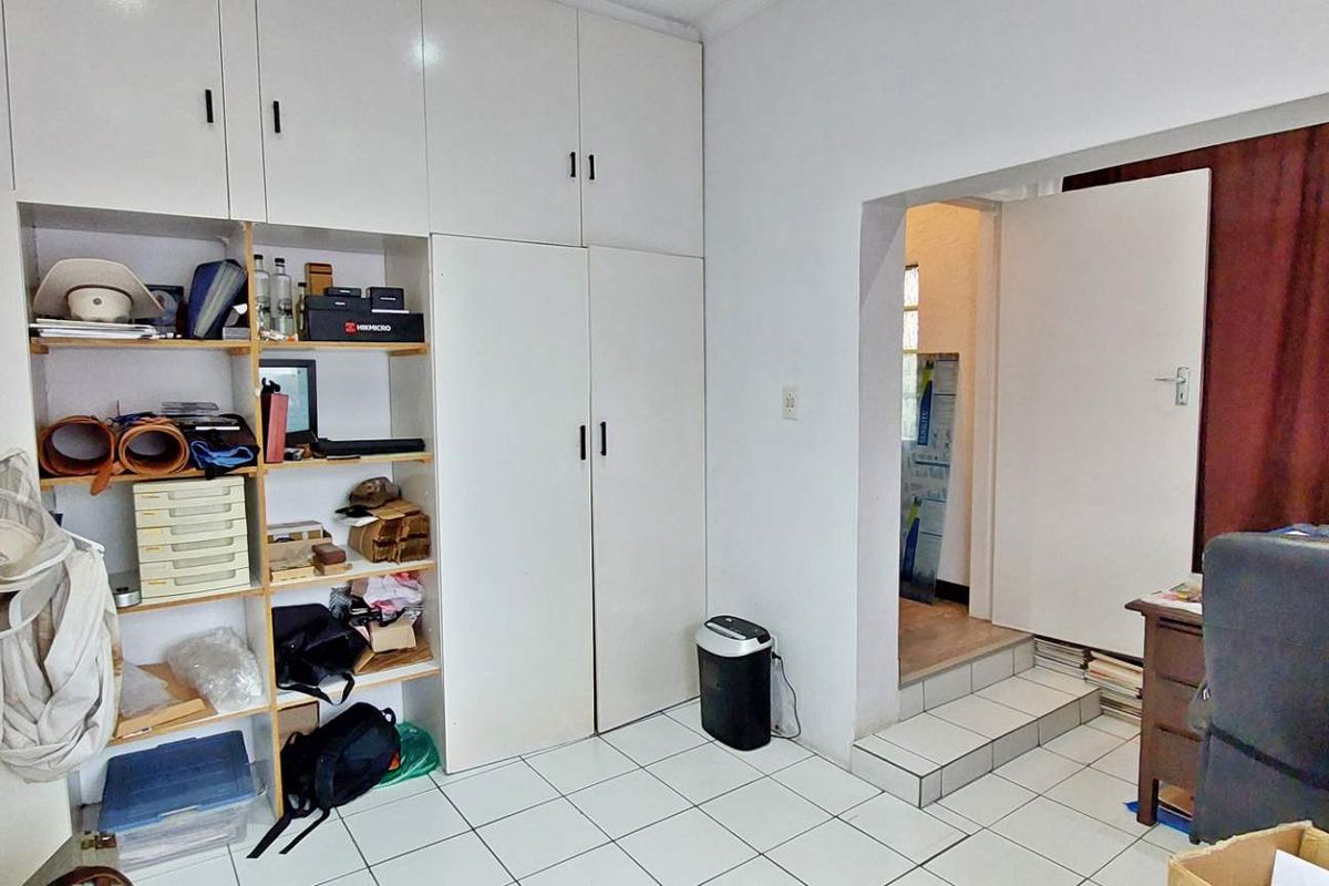 Bedroom featuring extensive built-in cupboard storage, tiled flooring, and a raised doorway leading to an adjacent space.