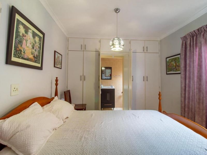 A well-lit bedroom featuring ample built-in cupboard storage and direct access to an en-suite bathroom.