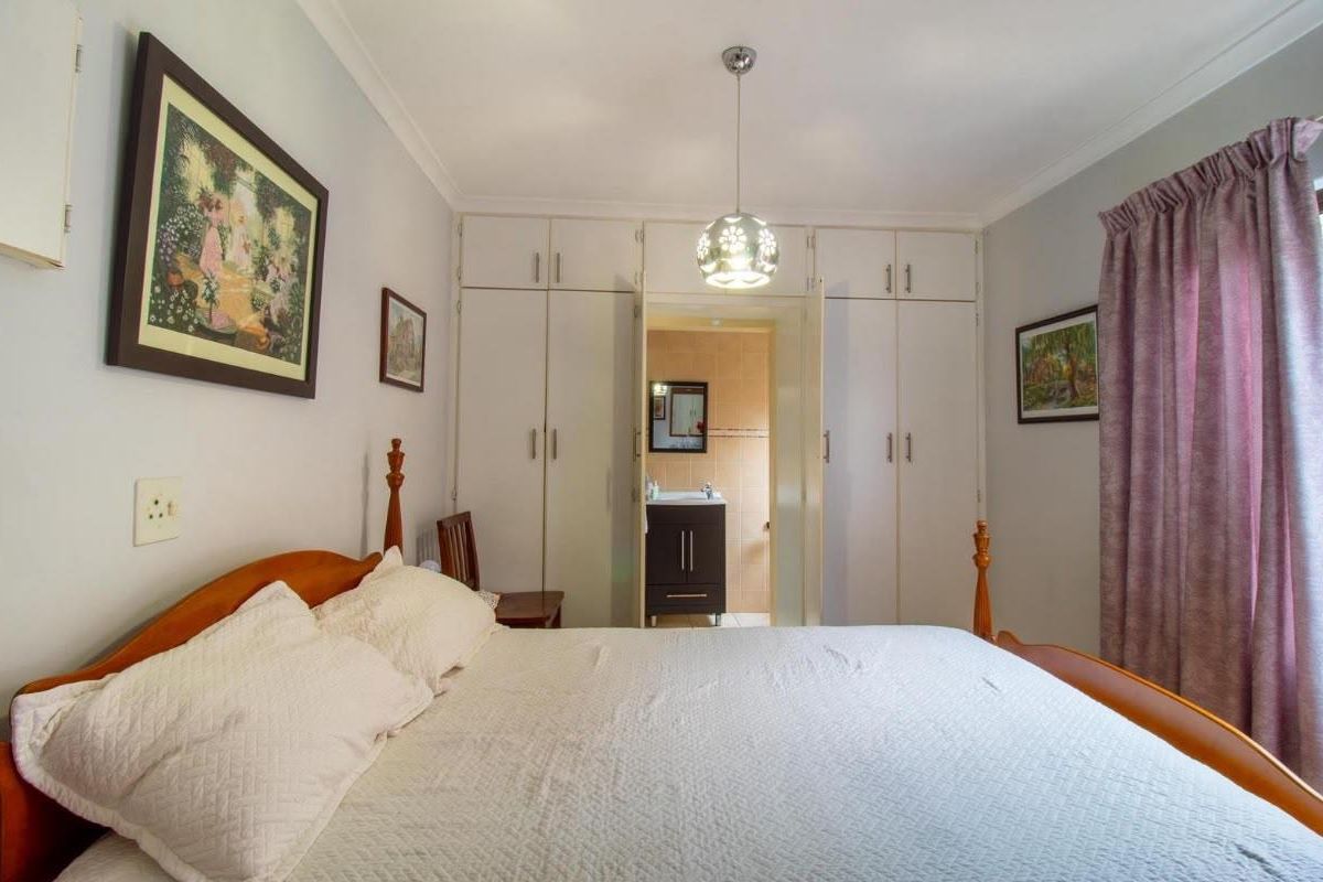 A well-lit bedroom featuring ample built-in cupboard storage and direct access to an en-suite bathroom.