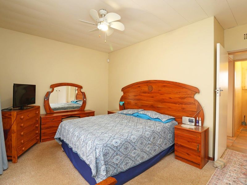 A carpeted bedroom featuring a ceiling fan, with an adjacent en-suite bathroom visible through the doorway.