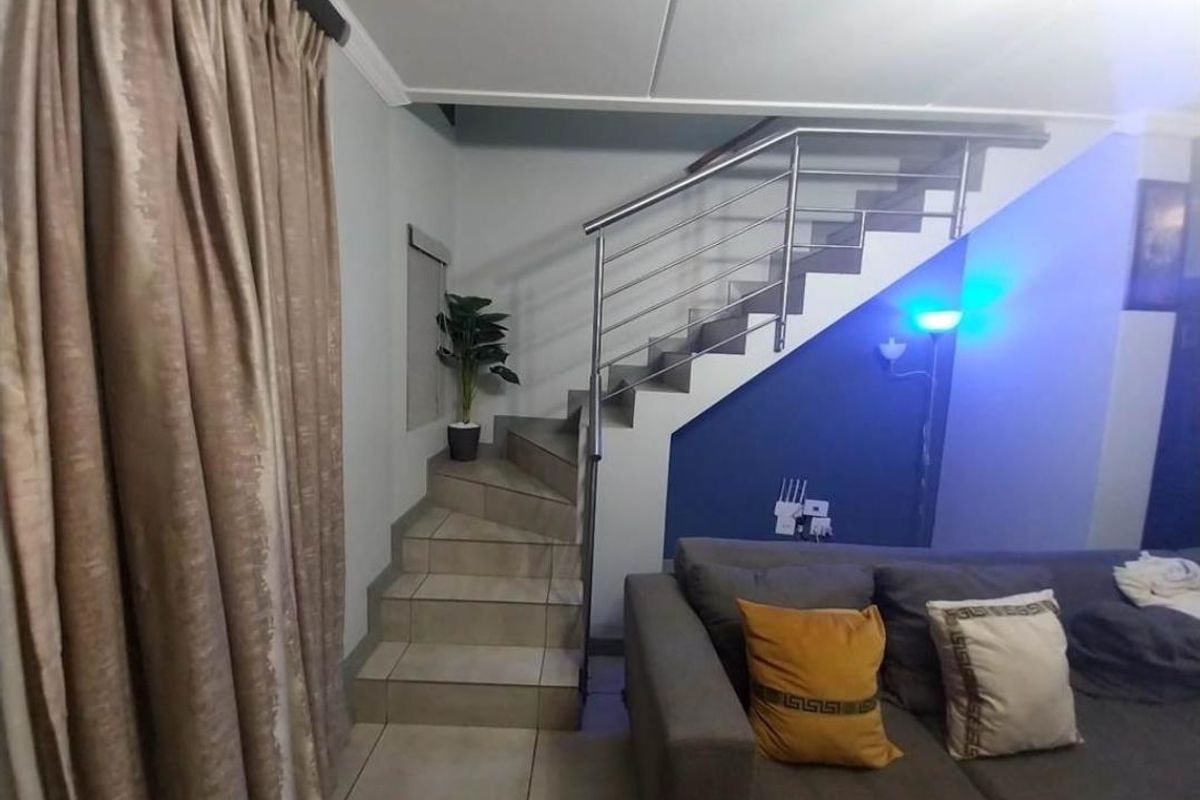 Interior view of a living area featuring a tiled staircase with a modern stainless steel balustrade and neutral wall finishes.