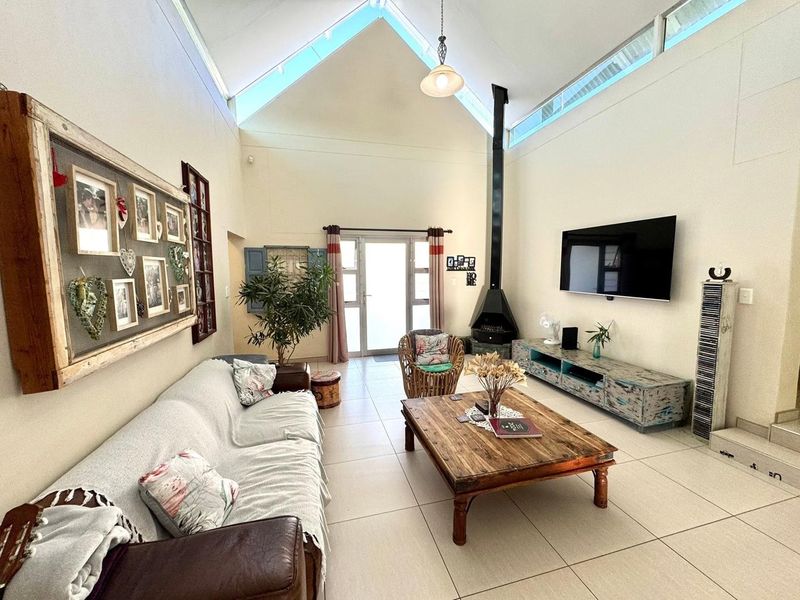 Spacious living room featuring a high vaulted ceiling with clerestory windows, tiled flooring, and a modern freestanding fireplace.