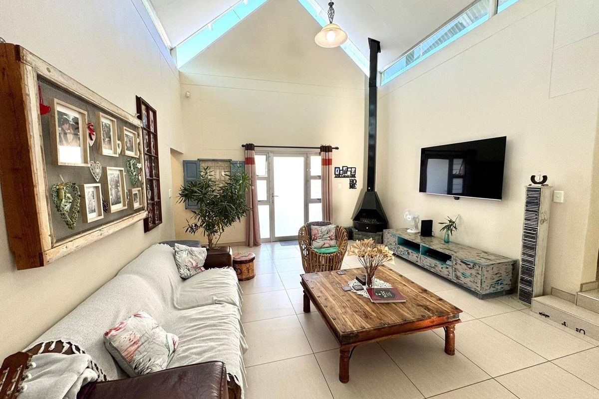 Spacious living room featuring a high vaulted ceiling with clerestory windows, tiled flooring, and a modern freestanding fireplace.