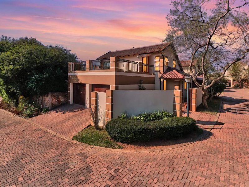 A well-maintained double-story residential property featuring a paved driveway, double garage, and an upper-level balcony with decorative iron railings.