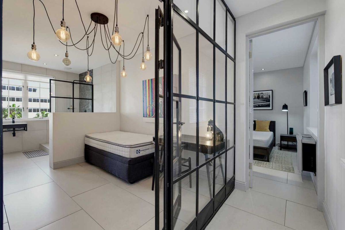 Modern bedroom featuring a stylish industrial steel and glass partition, tiled flooring, and an integrated en-suite bathroom area with contemporary finishes.