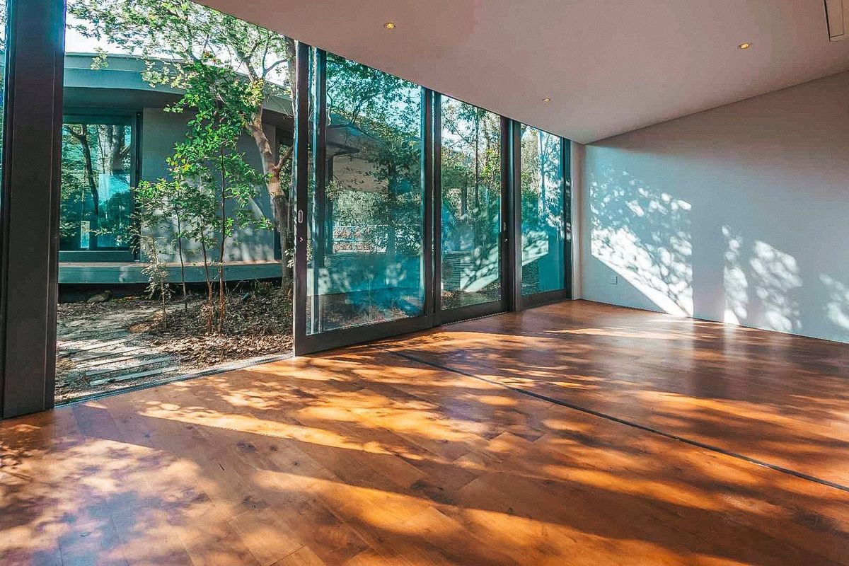Bright living area featuring expansive floor-to-ceiling sliding glass doors that open onto a private garden courtyard with hardwood flooring throughout.