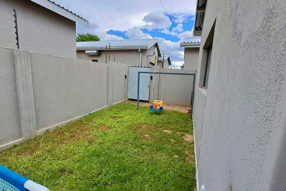 A compact rear garden area featuring high perimeter boundary walls with integrated electric fencing, providing a private outdoor space for the townhouse.