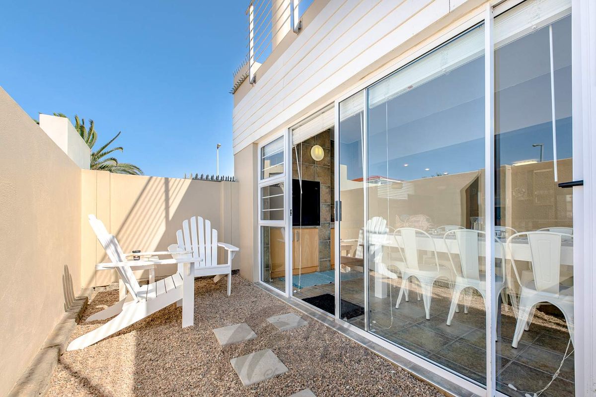 A private rear courtyard featuring a gravel surface, paved stepping stones, and large sliding glass doors providing access to the interior living space.