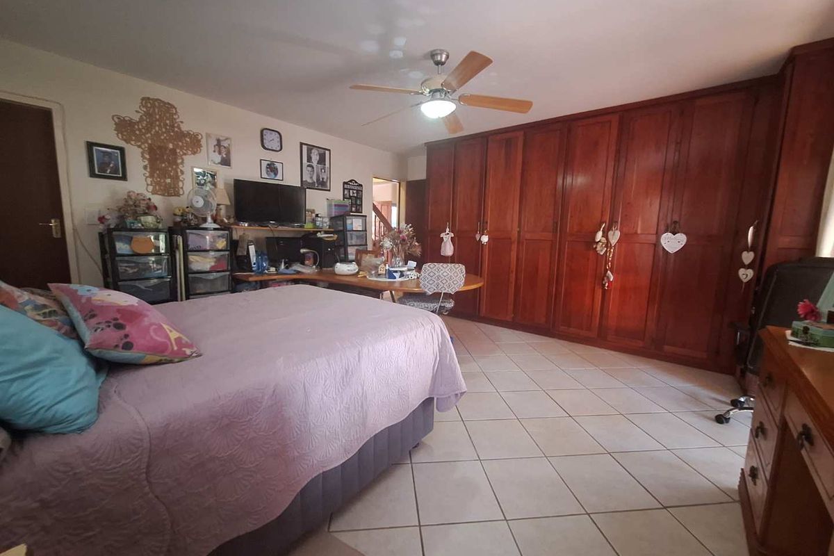 Spacious bedroom featuring extensive built-in wooden cabinetry, tiled flooring, and a ceiling fan.