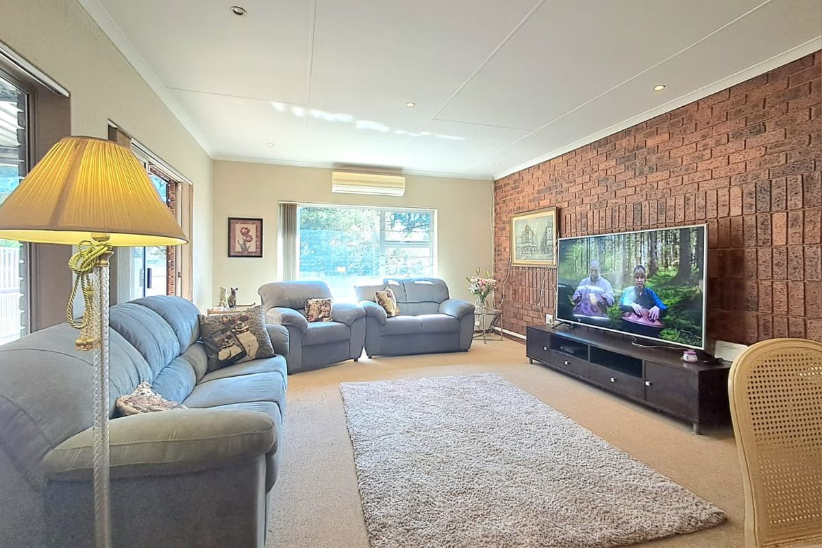 Spacious living room featuring a prominent exposed brick feature wall, recessed ceiling lighting, and a wall-mounted air conditioning unit.