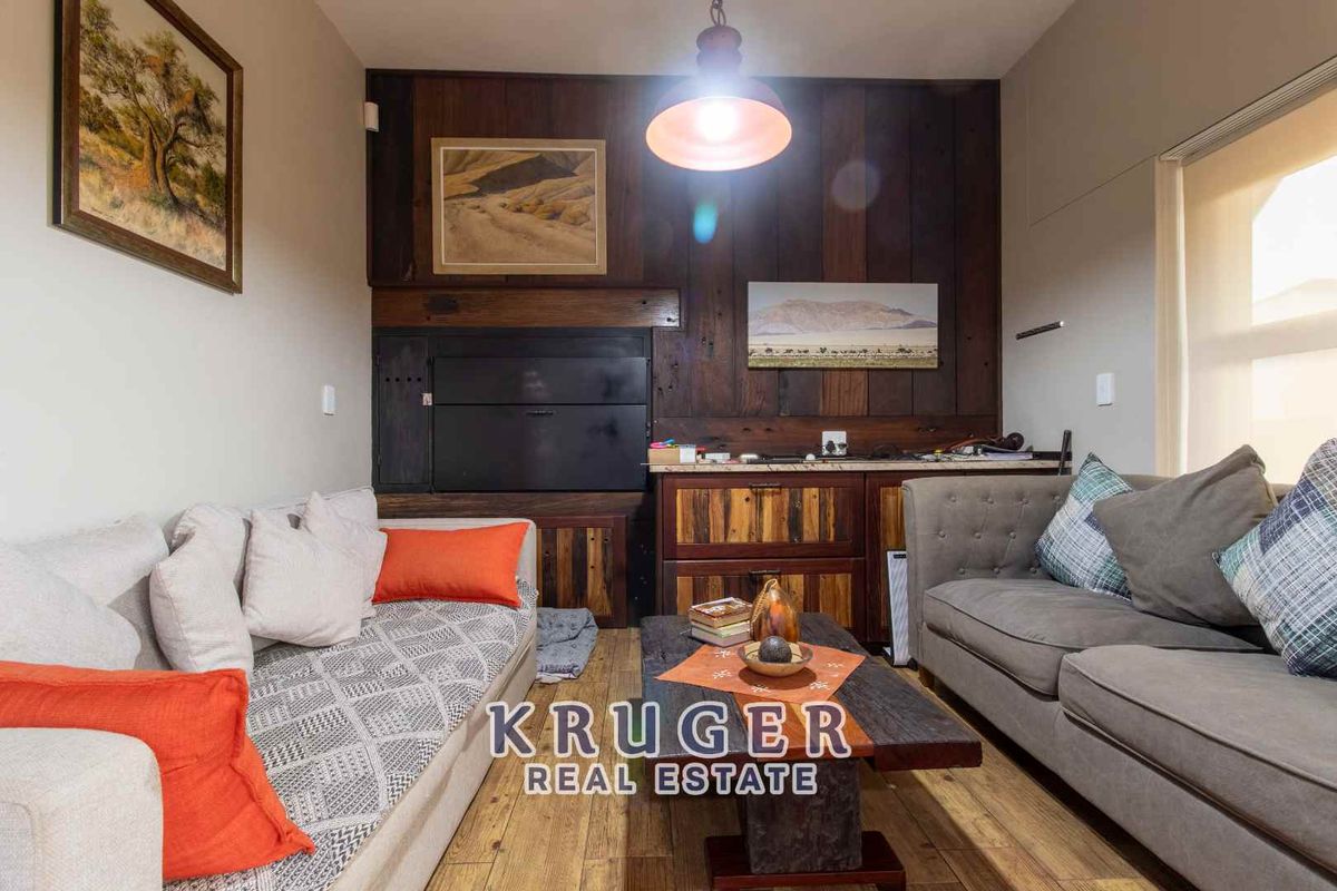 A cozy living room featuring a built-in fireplace and custom wood-paneled feature wall with integrated cabinetry.