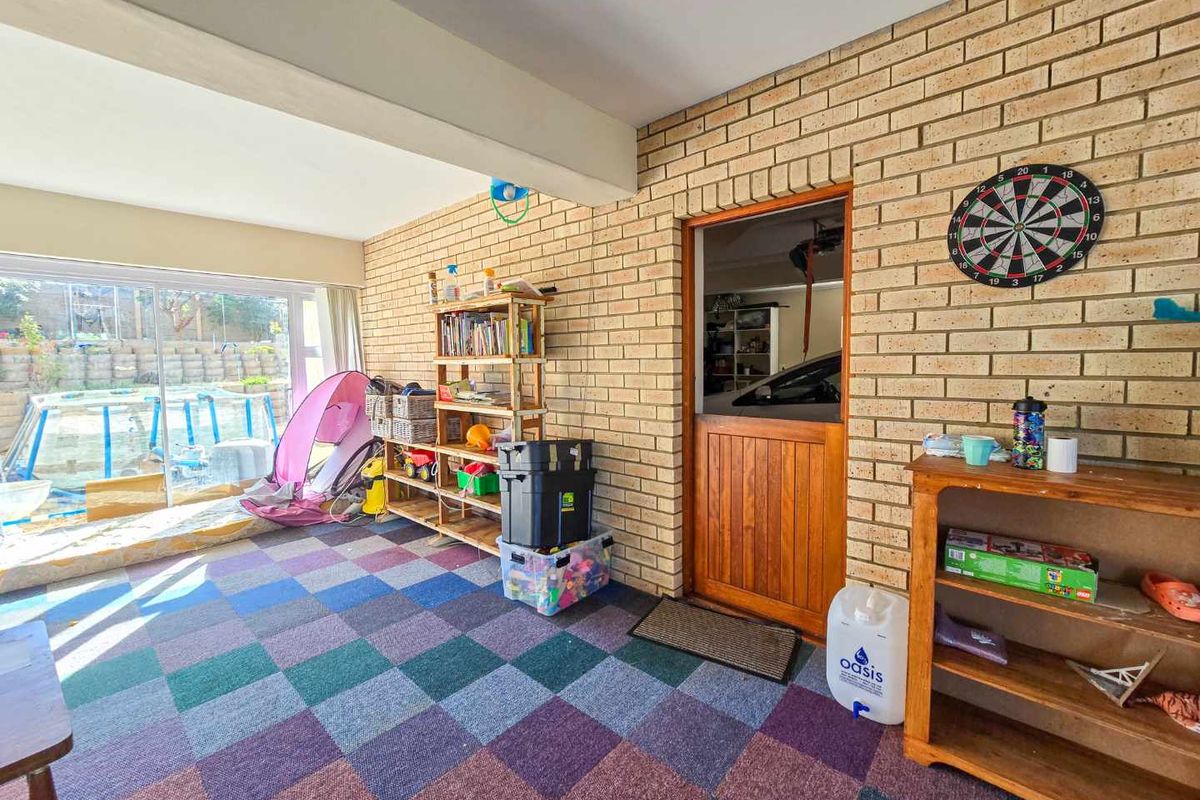 A versatile indoor living space featuring exposed brick walls, large sliding glass doors leading to the garden, and direct access to the garage.