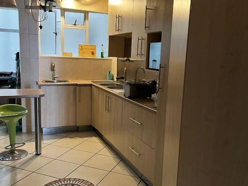A functional kitchen featuring light wood-tone cabinetry, tiled flooring with a decorative inlay, and a built-in breakfast bar area.