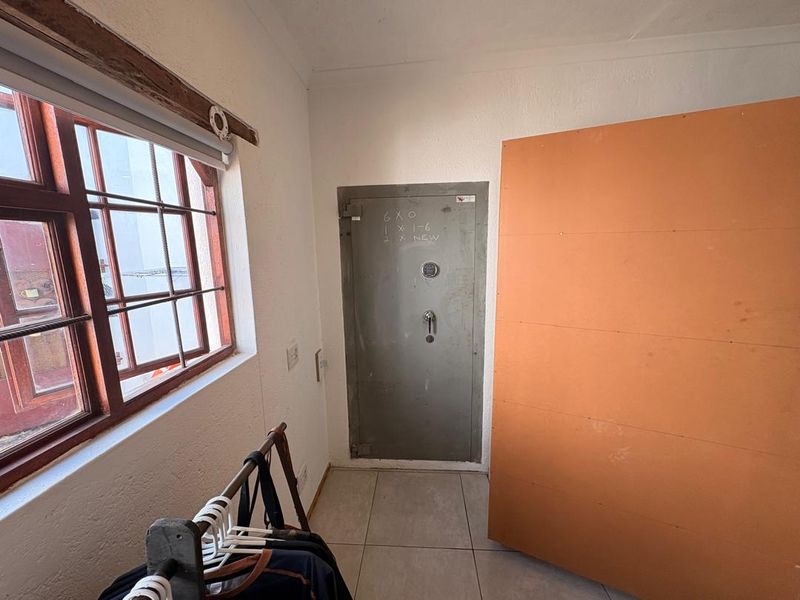 A utility space featuring a heavy-duty security vault door, tiled flooring, and a timber-framed window, offering a secure storage area.
