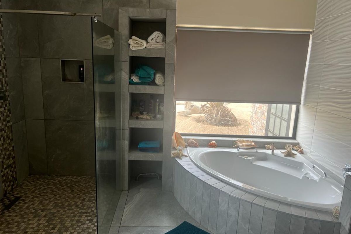 Modern bathroom featuring a corner soaking tub, a walk-in shower with glass enclosure, and built-in tiled shelving.