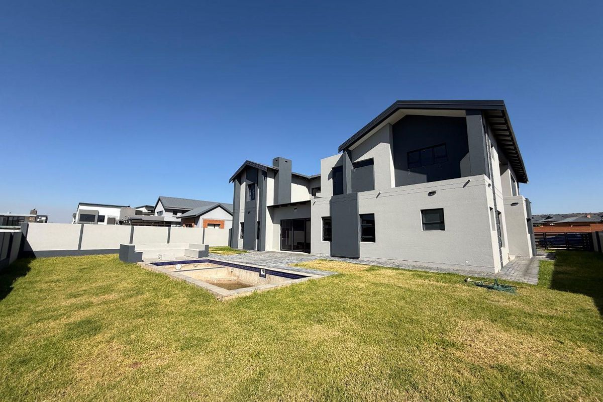 Rear view of a modern two-story house featuring a paved patio area, a swimming pool, and a private garden.