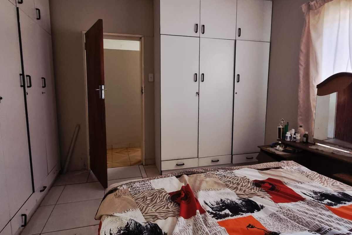 A bedroom featuring extensive built-in cabinetry and tiled flooring, providing ample storage space and direct access to an adjoining room.