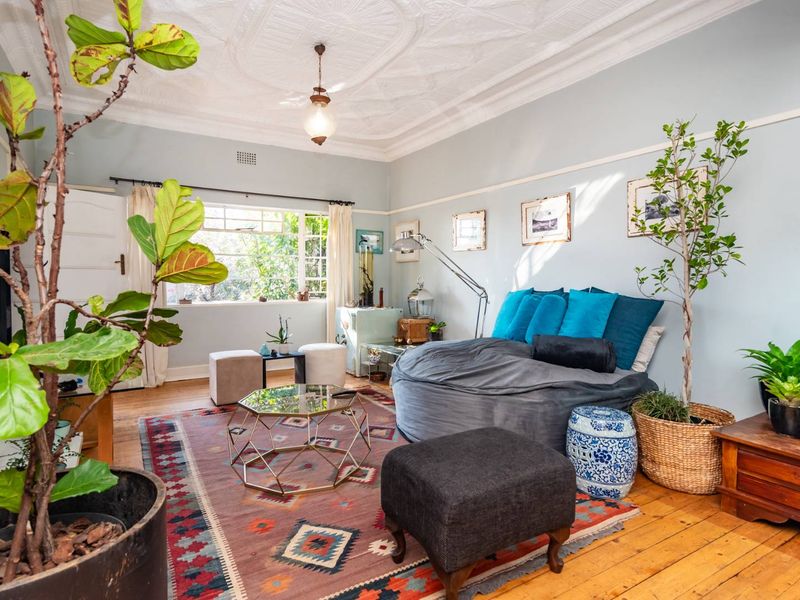 A character-filled living room featuring original timber flooring, an ornate pressed metal ceiling, and classic picture rails, offering a warm and inviting atmosphere.