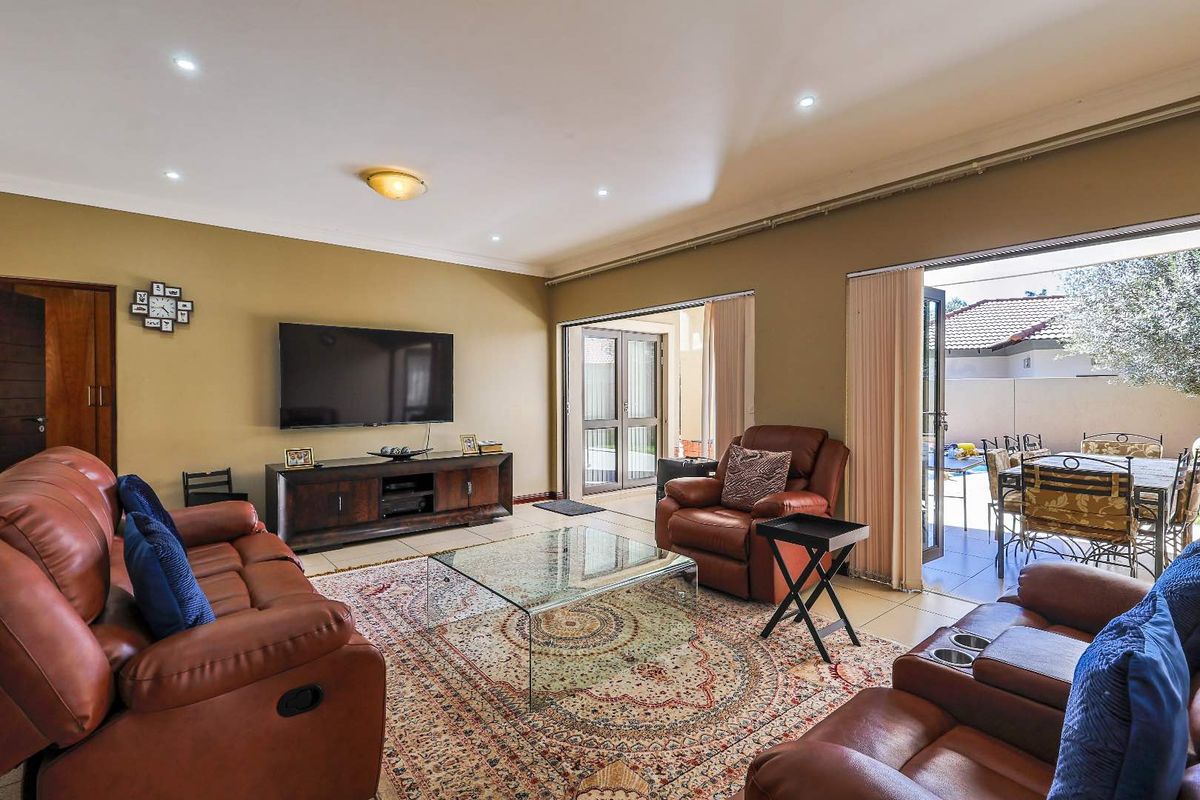 Spacious living room featuring tiled flooring, recessed downlighting, and large sliding glass doors providing seamless access to the outdoor patio area.