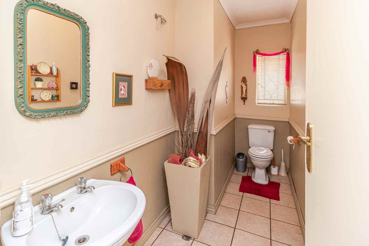 A compact guest bathroom featuring a pedestal sink, a standard toilet, and tiled flooring with a dado rail finish.