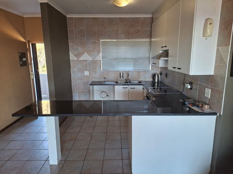 A functional kitchen featuring granite countertops, tiled backsplash, and built-in cabinetry, with an open-plan breakfast bar area.