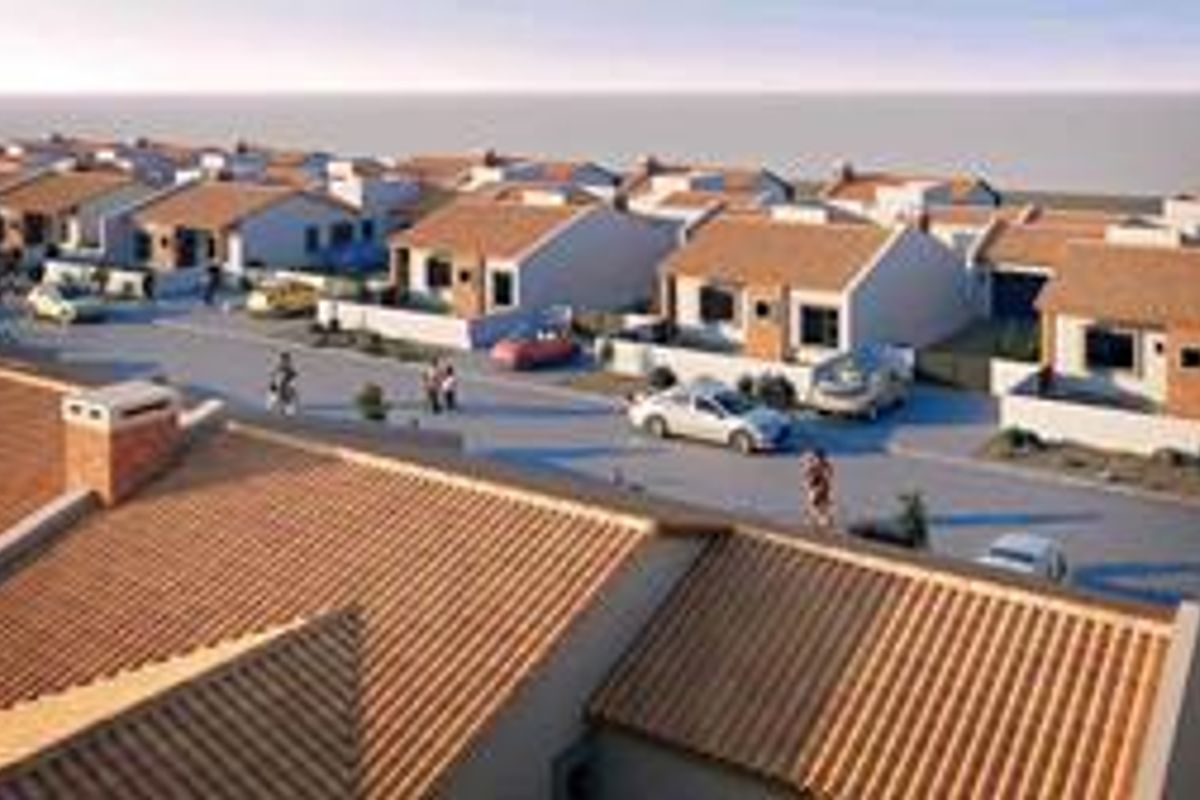 An aerial view of a residential townhouse development featuring uniform architectural design, tiled roofs, and paved street access.