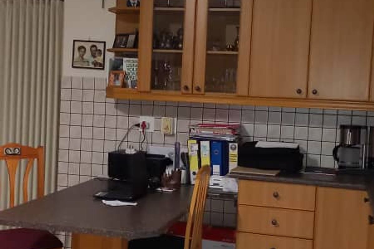A functional kitchen area featuring wooden cabinetry, tiled backsplash, and integrated dining counter space with tiled flooring.