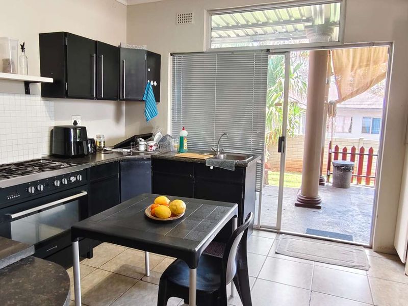 Functional kitchen featuring dark cabinetry, gas hob, oven, and direct access to the outdoor patio area through a sliding glass door.