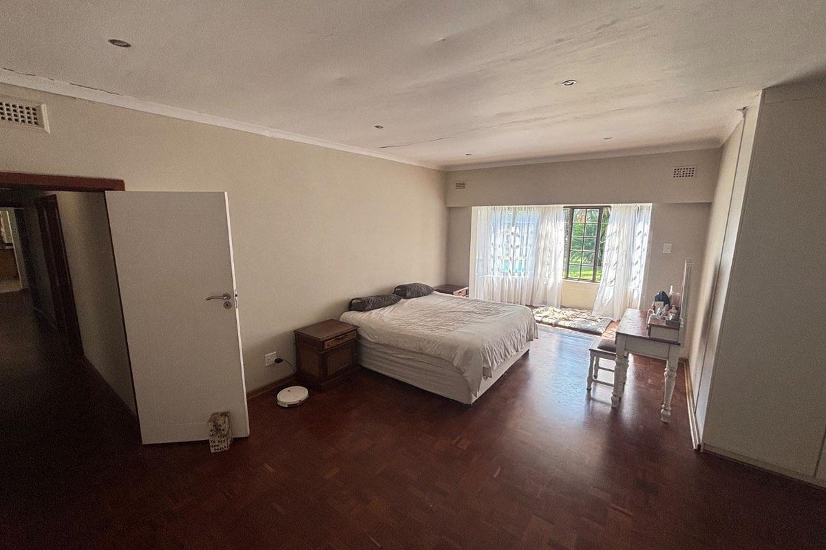 Spacious bedroom featuring polished parquet flooring, recessed downlighting, and large windows allowing for natural light.