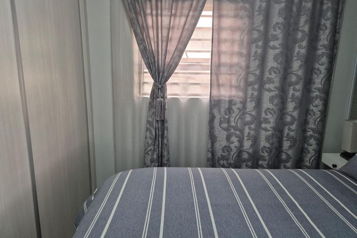 A bedroom featuring built-in cabinetry and a window with curtains.
