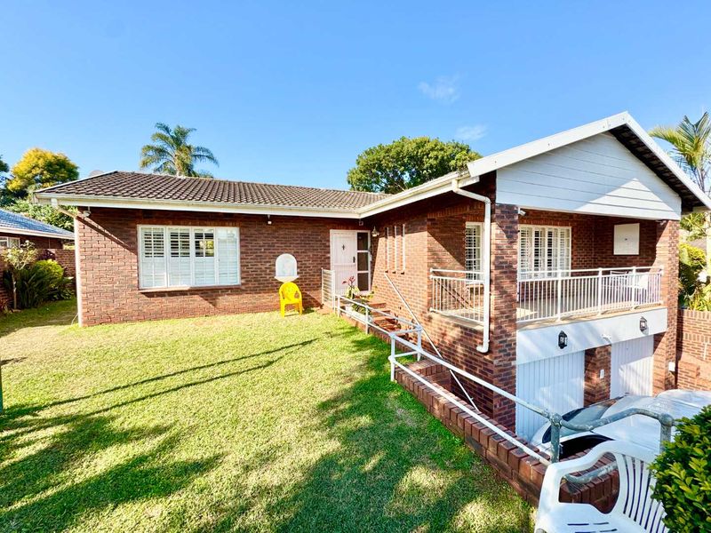 A well-maintained face brick family home featuring a tiled roof, double garage, and a spacious front lawn with secure metal balustrades.