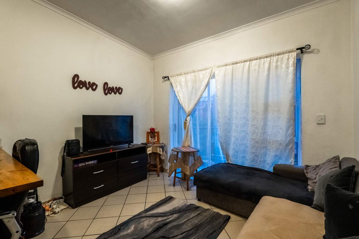 A living room featuring tiled flooring and a sliding glass door providing access to an outdoor area.