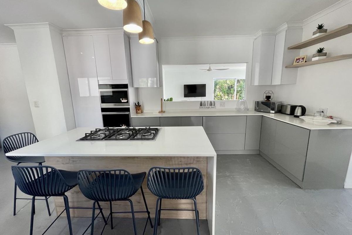 Modern kitchen featuring a central island with gas cooktop, sleek cabinetry, stone benchtops, and integrated appliances, offering a clean and functional culinary space.