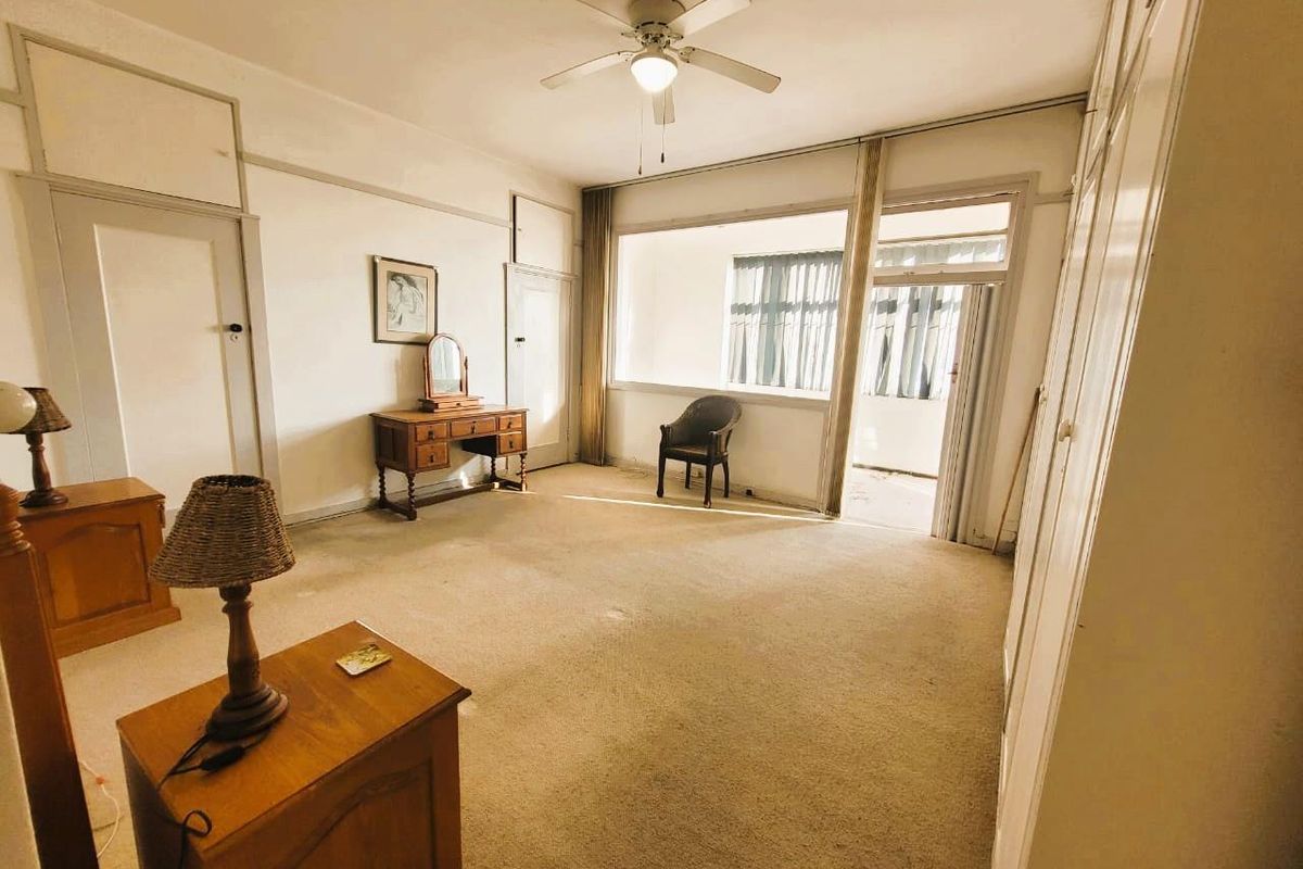Spacious bedroom featuring built-in cupboards, a ceiling fan, and direct access to an adjoining balcony through a glass door.