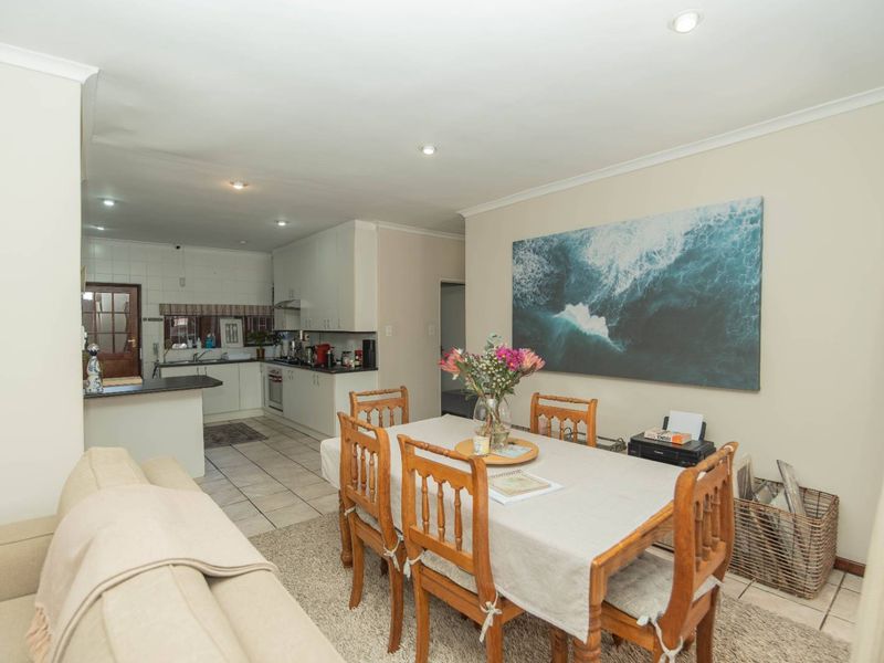 Open-plan living and dining area flowing into a functional kitchen with built-in cabinetry, oven, hob, and tiled flooring throughout.