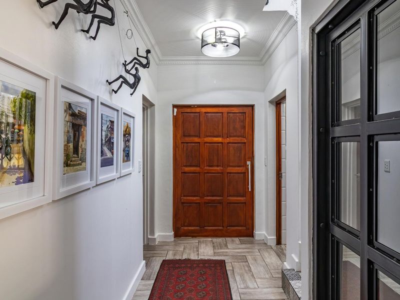 A welcoming entrance hall featuring a solid timber front door, tiled flooring, and decorative crown molding, creating a bright and well-maintained transition space.