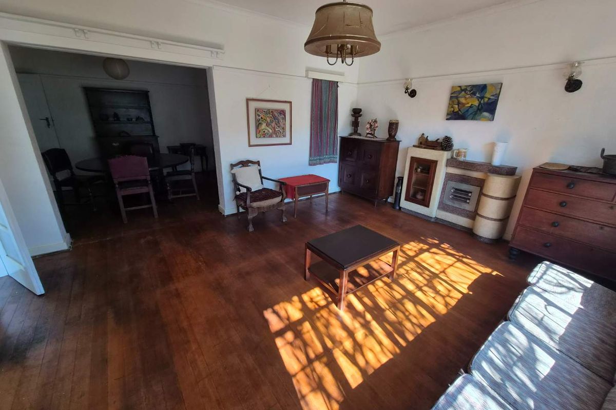 Spacious living room featuring original hardwood flooring, a built-in fireplace, and classic architectural details like picture rails and coved ceilings.
