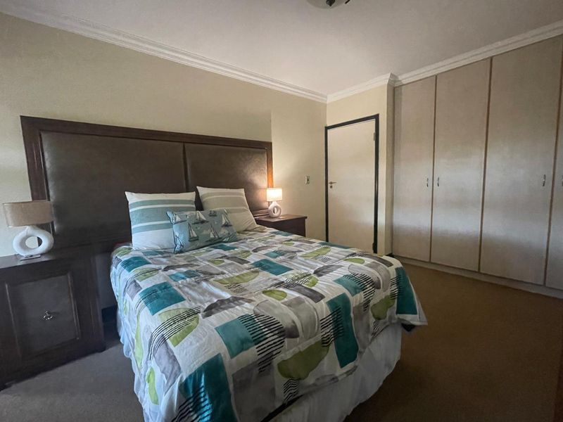 A bedroom featuring built-in cupboards, crown molding, and carpeted flooring.