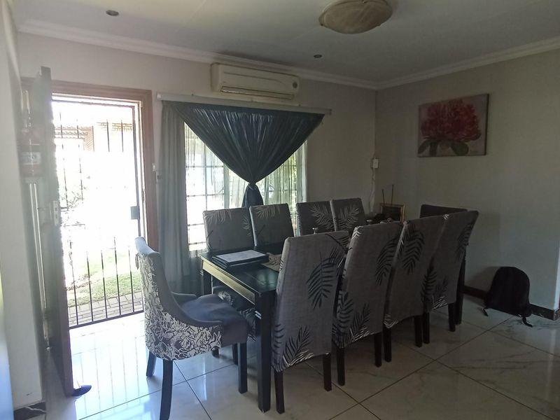 A dining room featuring tiled flooring, an air conditioning unit, and direct access to the exterior through a security gate.