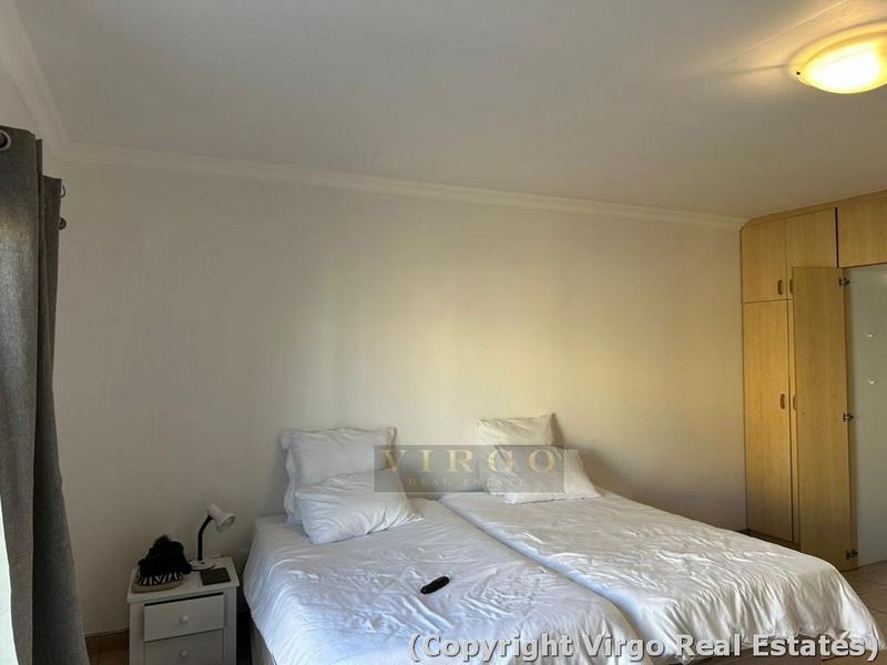 A bedroom featuring built-in wooden cupboards and neutral wall finishes, providing a functional and tidy sleeping space.